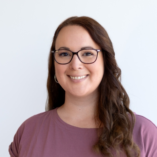 Katrin steht vor einer weißen Wand und lächelt