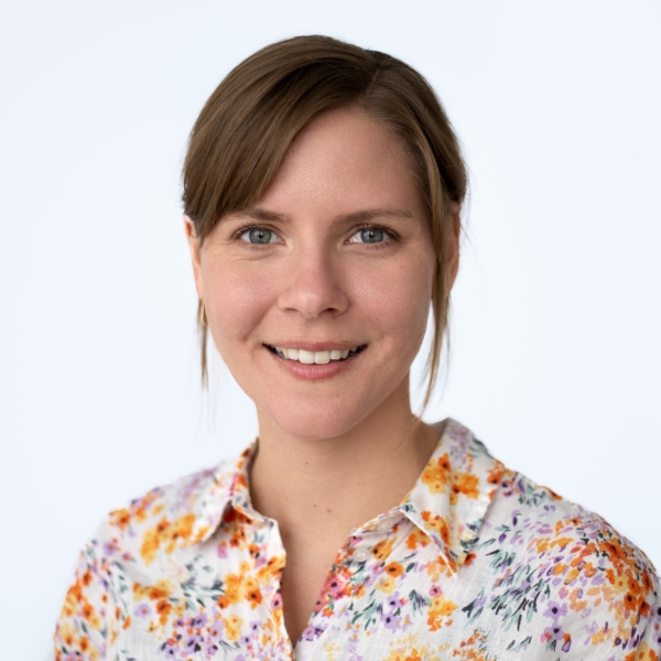 Sarah-Lisa-Knittler lächelt in die Kamera und trägt eine geblümte Bluse.