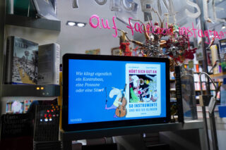Bildschirm mit Buchempfehlung hinter einem Schaufenster