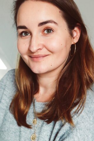 Jessica Haedecke vom Blog "Miss Paperback" steht vor einem weißen Hintergrund und lächelt.