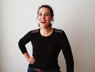 Katharina vom Blog "Die lesende Käthe" steht vor einem weißen Hintergrund und lächelt.