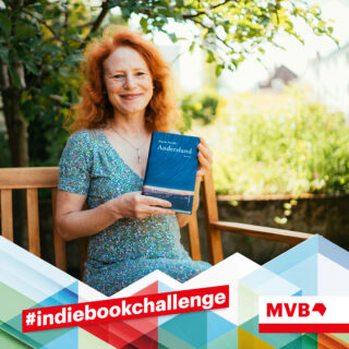 Susanne Fuchs hält im Rahmen der Indiebookchallenge im Juni das Buch "Andersland" in den Händen und lächelt.