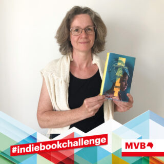 Monica Wellmann hält im Rahmen der Indiebookchallenge im Juni das Buch "Halt" in den Händen und lächelt.