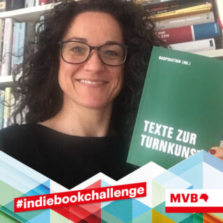 Susanne Schneider hält im Rahmen der indiebookchallenge im November das Buch "Texte zur Turnkunst" in den Händen und lächelt.