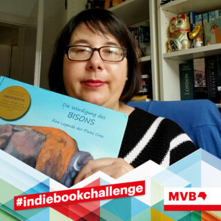 Viola Hilz hält im Rahmen der indiebookchallenge das Buch "Die Würdigung des Bisons" in den Händen und lächelt.