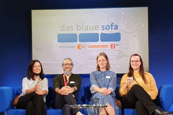 Ines, Markus, Angie und Katrin sitzen auf dem blauen Sofa.