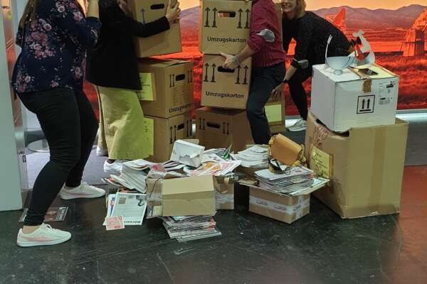 Das Messeteam trägt Pappkartons beim Abbau der Messe.