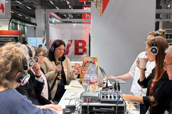 Mehrere Menschen tragen Kopfhörer und sitzen zusammen an einem Tisch