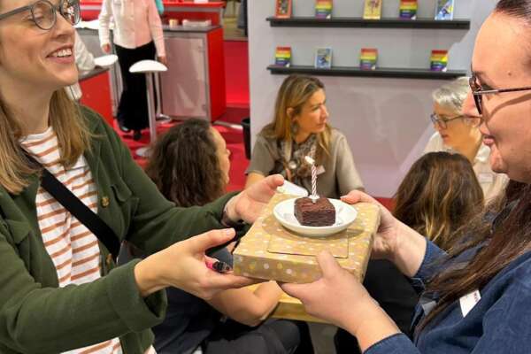 Angie Timplan übergibt Katrin Friedl ein Geschenk und ein Kuchenstück mit Kerze