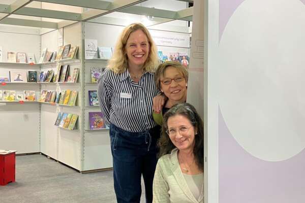 Katharina, Susanne und Frauke schauen, die Köpfe übereinander, hinter einem Livro-Aufsteller hervor