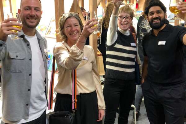 Michael, Sophie, Liz und Jag stehen nebeneinander und heben Gläser hoch