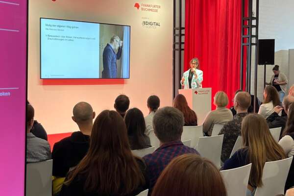 Susanne Breuer steht mit Mikro auf einer Bühne