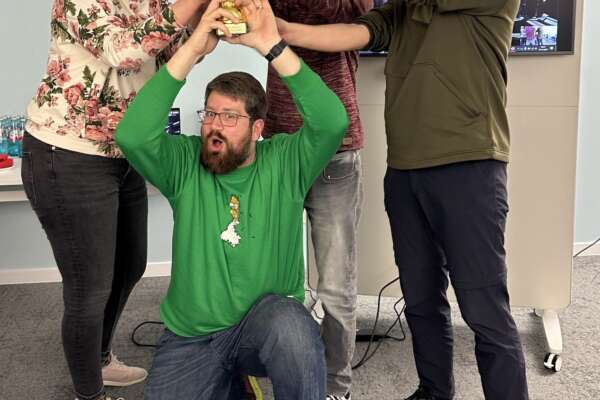Das 4-köpfige Gewinnerteam des Hackathon Team Code Busters  jubelt und hält dabei den gewonnen Pokal hoch.