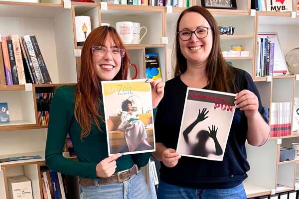 Lorina und Katrin halten jeweils ein Lesemotiv-Plakat in den Händen.