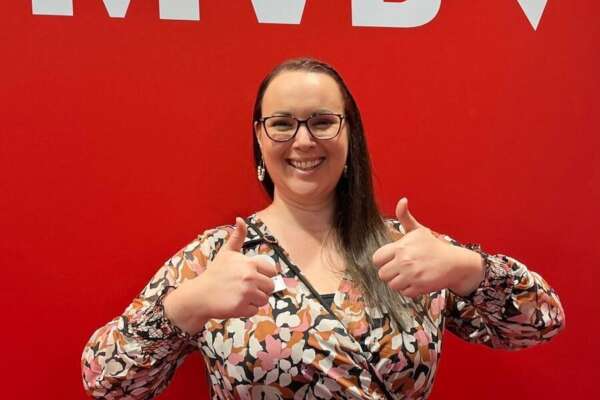 Katrin steht unter dem MVB-Logo mit hochgehaltenen Daumen.