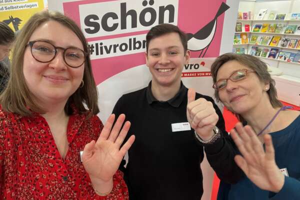 Das Livro-Team steht vor der Fotowand und lächelt in die Kamera.