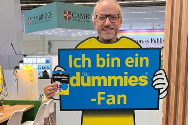 Markus hält ein Exemplar Lesemotive für Dummies in den Händen und ein Schild, auf dem steht "Ich bin ein dummies-Fan"