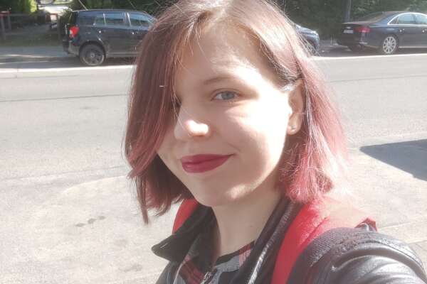 Anna lächelt auf dem Weg zur Arbeit in die Kamera.