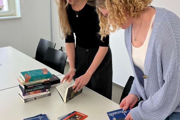 Emely und Ronja widmen Bücher für den Welttag des Buches.