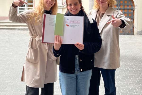 Ronja, Jule und Emely zeigen auf ein von uns signiertes Buch.