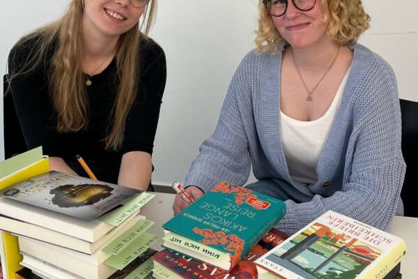 Emely und Ronja widmen Bücher für den Welttag des Buches.