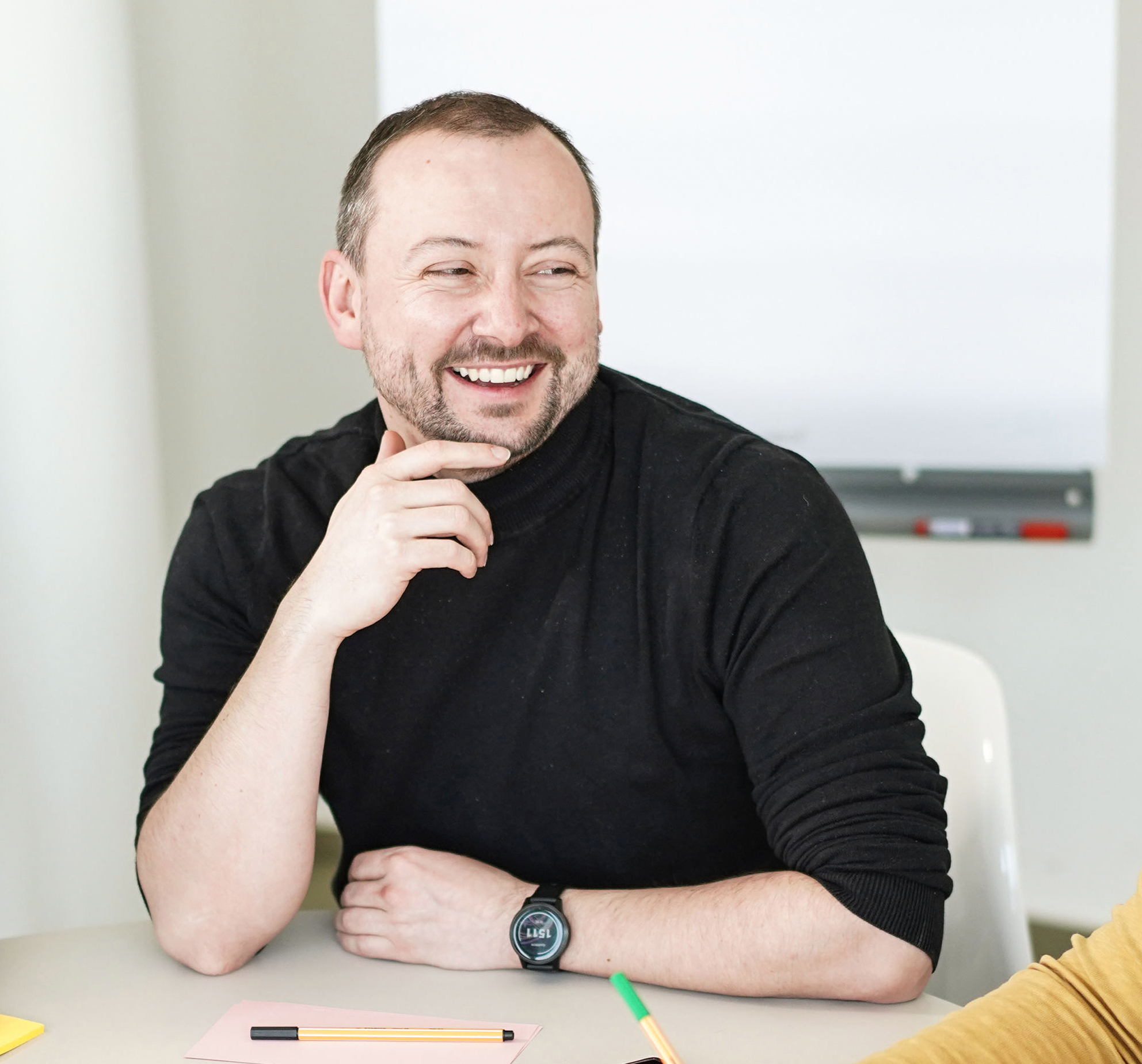 Paul sitzt am Tisch und freut sich.