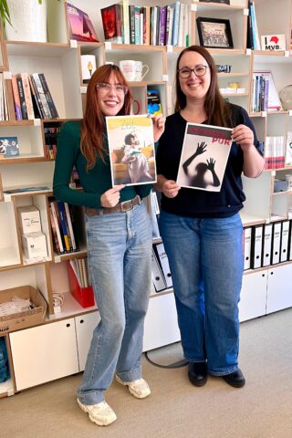 Katrin und Lorina halten jeweils ein Lesemotiv-Plakat in den Händen.