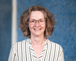 Portrait von Monica Wellmann vor einem blauen Hintergrund