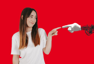 Frau berührt mit ihrem Finger den Finger einer Roboterhand